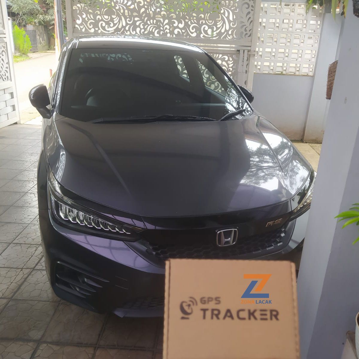 Mobil sedan di garasi dengan kemasan GPS Tracker Zona Lacak di depannya